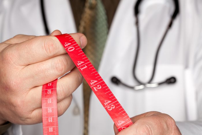 Doctor with Stethoscope Holding Red Measuring Tape.