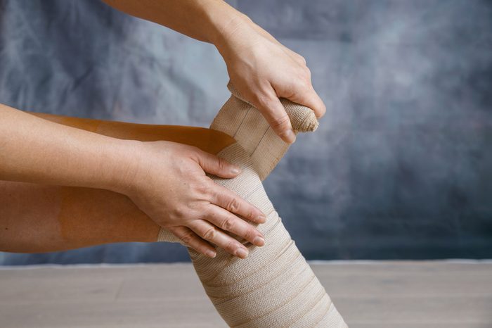 Person wrapping a compression bandage on their leg.