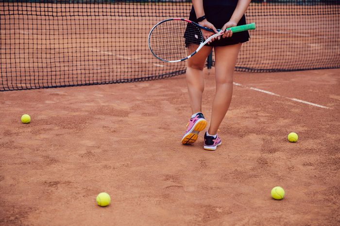 Woman holding a tennis racket on a clay tennis court.