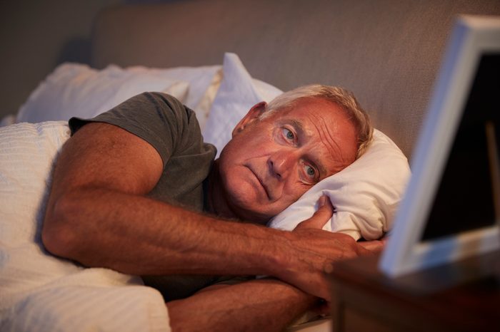 man laying awake in bed at night trying to sleep