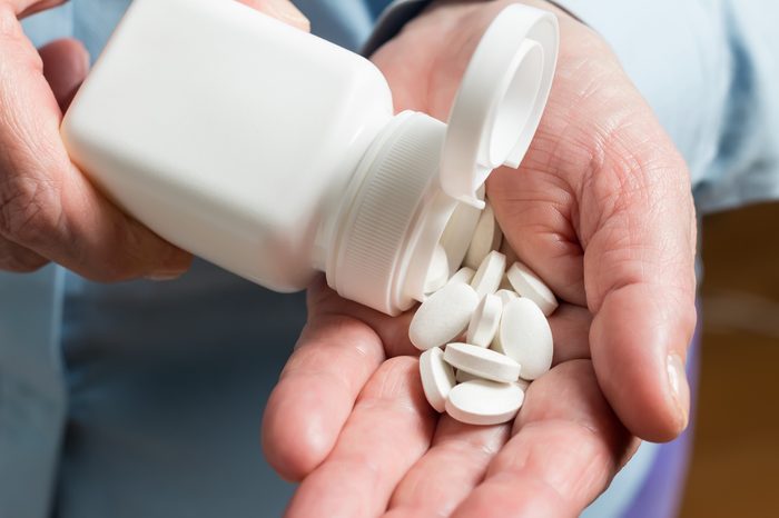 pouring white medication pills into hand