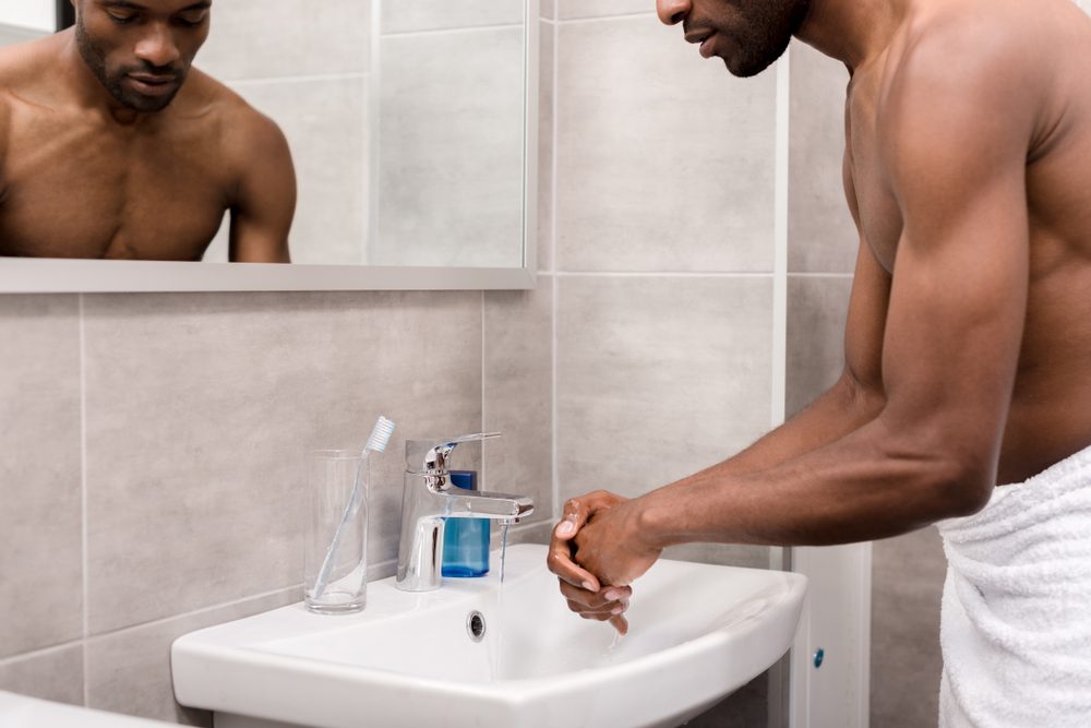 man in towel washing his hands 