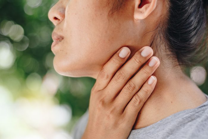 woman holding neck and throat