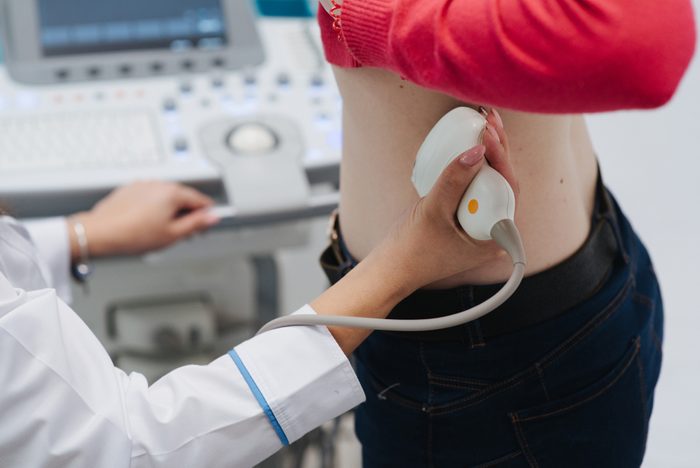 Renal ultrasound examination of kidneys. Hospital doctor examines a young woman with ultrasound.