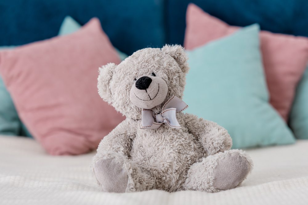 teddy bear sitting on a bed with pillows