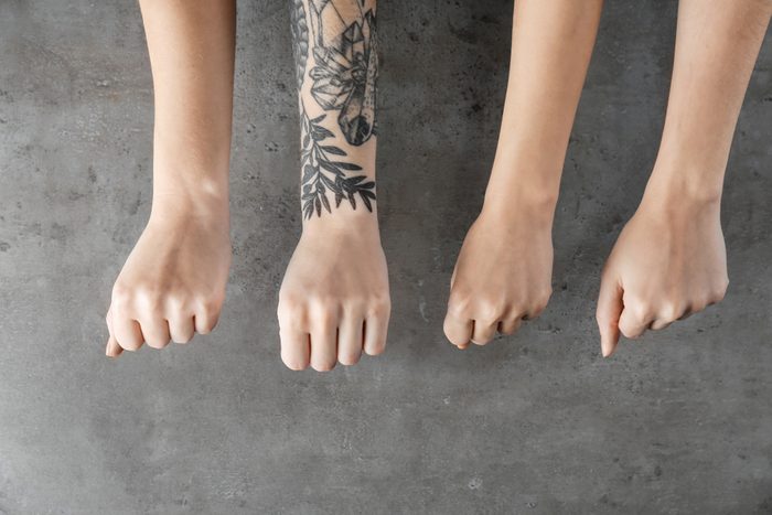 Person with tattoo standing out from others on grey background. Think different concept
