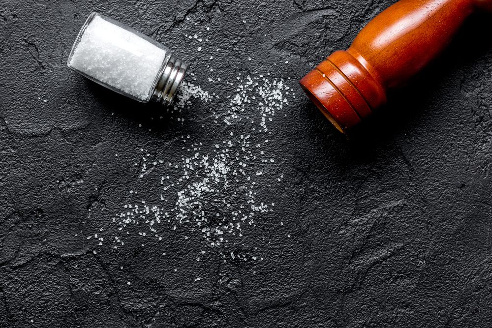 salt and saltcellar on black stone table background top view mock-up