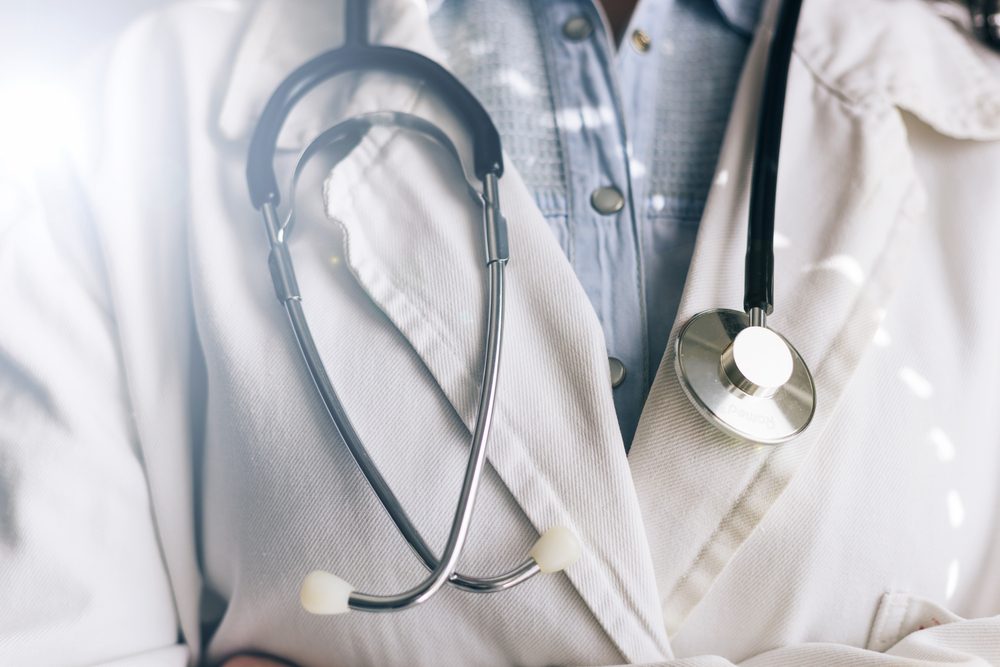 Medical doctor on white background holding a stethoscope. Focus on the stethoscope.