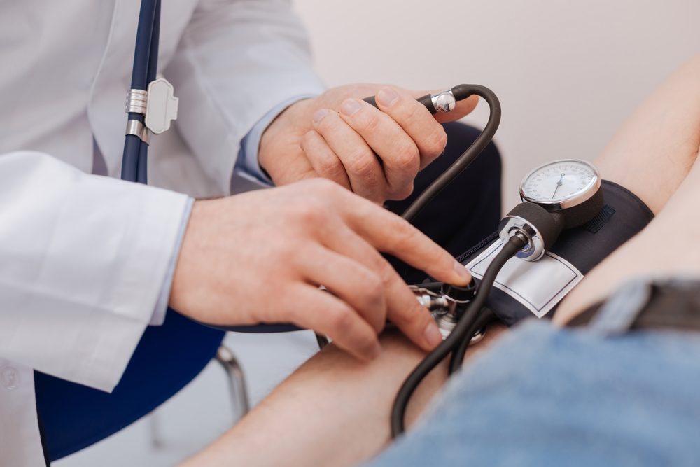 Nice careful medical worker employing a blood pressure sensor