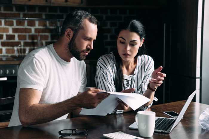 young couple counting bills together on kitchen at home