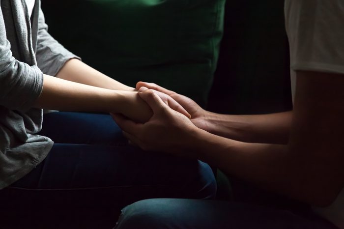 sad depressed couple hold hands dark