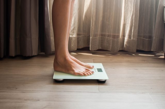 woman standing on scale close up of legs and feet