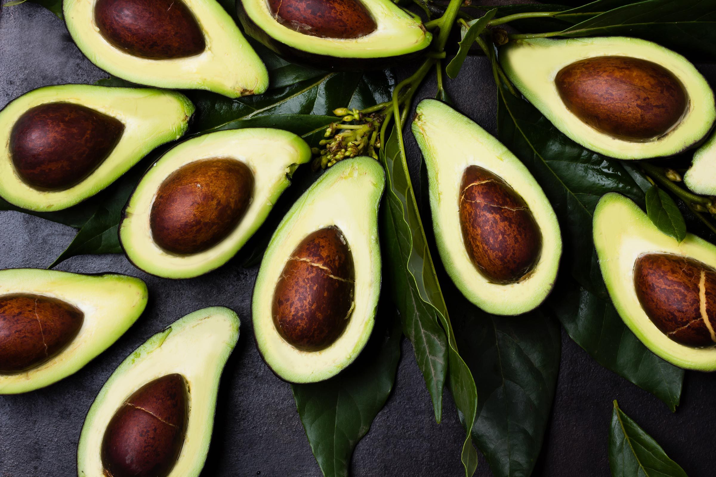 Avocado. Fresh avocado palta with leaves on black background. Guacamole ingredient. Vegetarian or healthy eating. Healthy fat