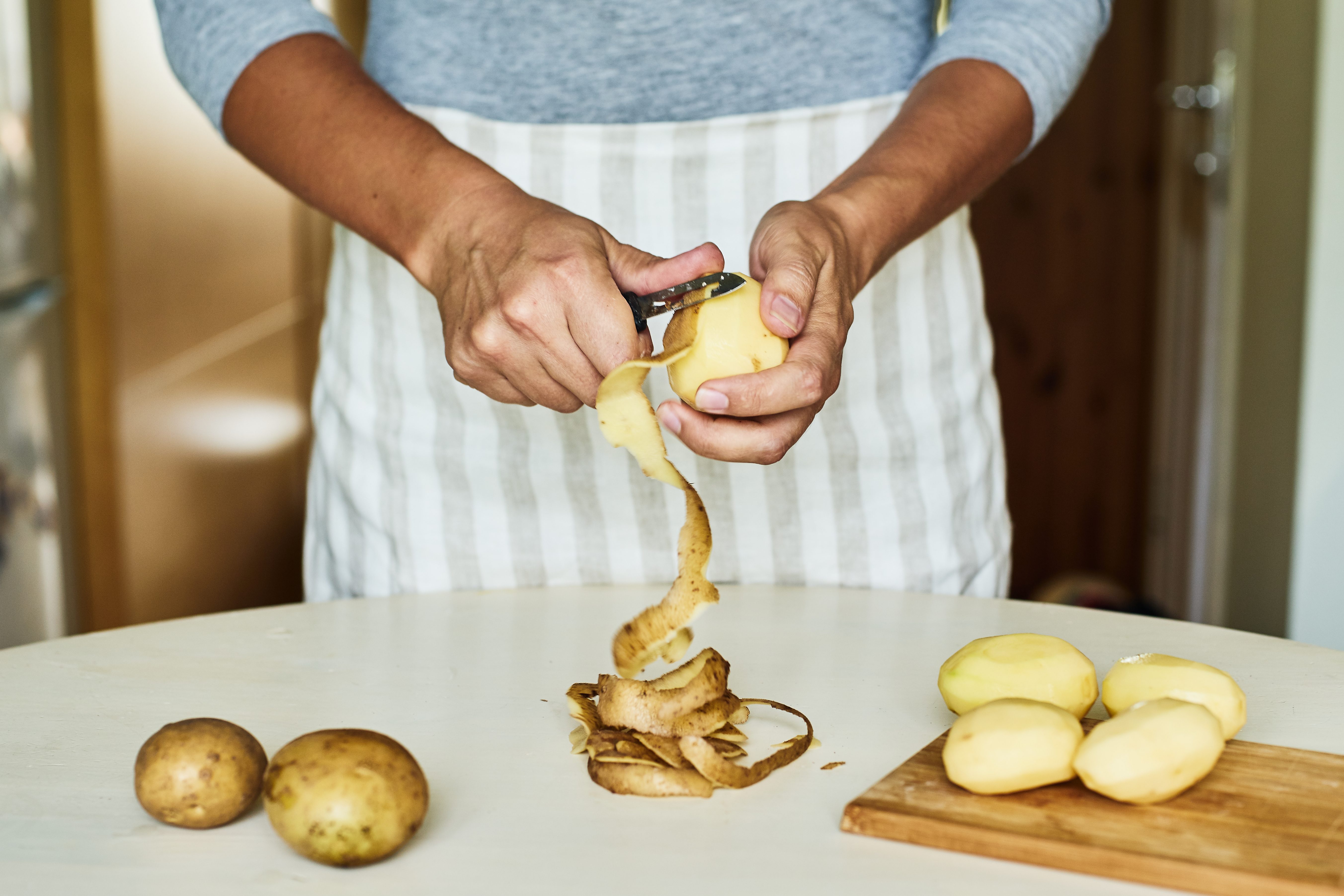 Peeling some potatoes on white table 