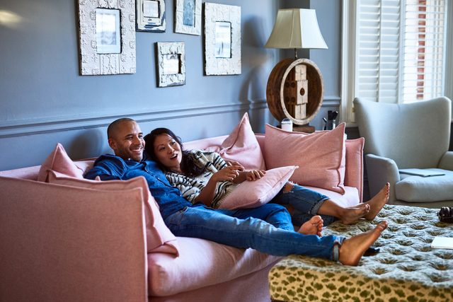 couple sitting on couch at home relaxing and laughing together