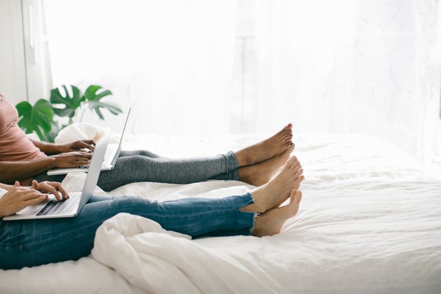 laying in bed using laptops
