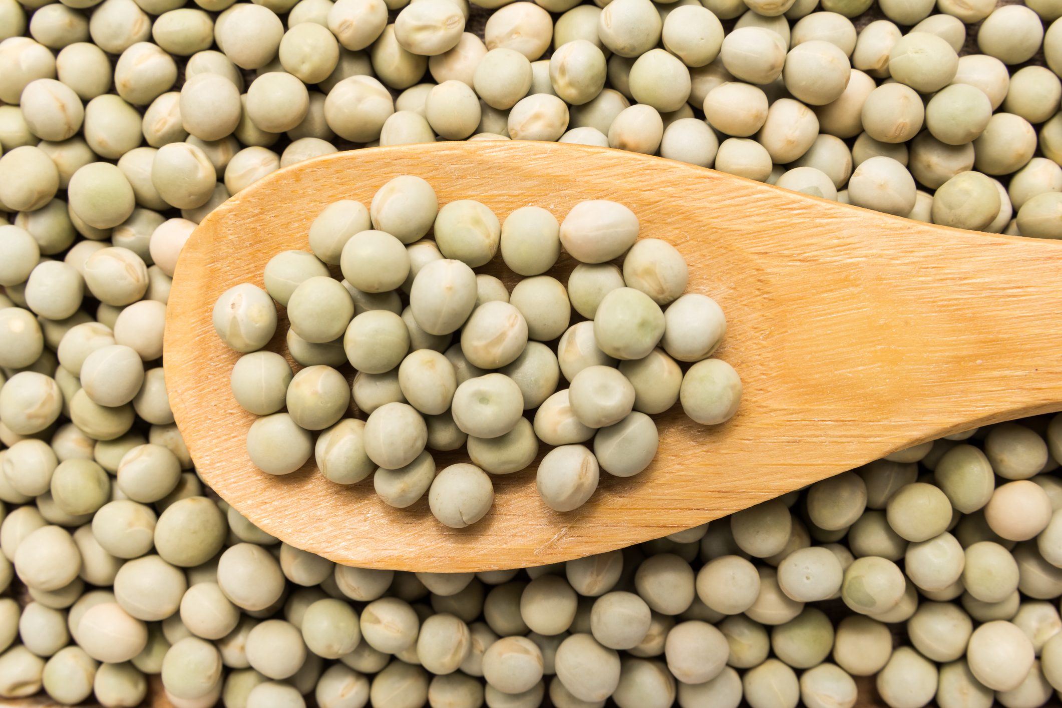 green peas in wooden spoon shot from above