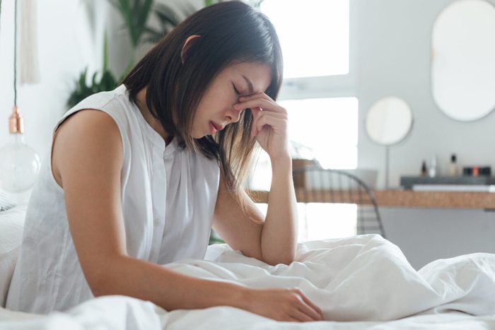 Young Woman Suffering Headache In Bed