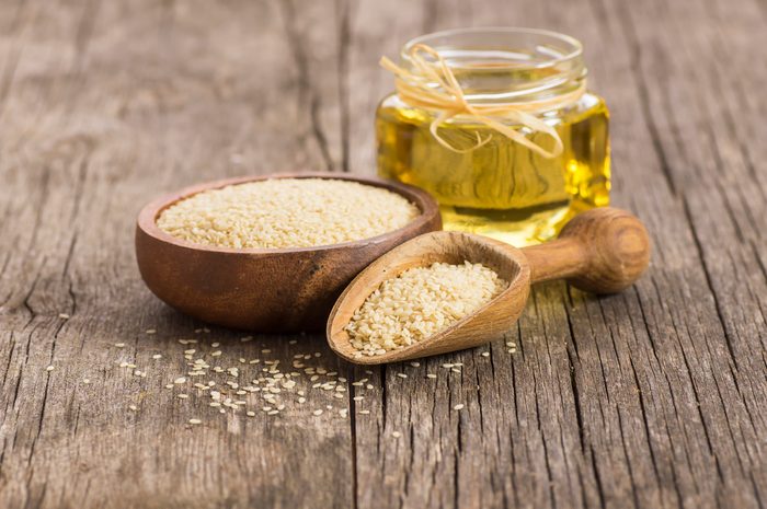 Glass bottle of sesame oil and raw sesame seeds