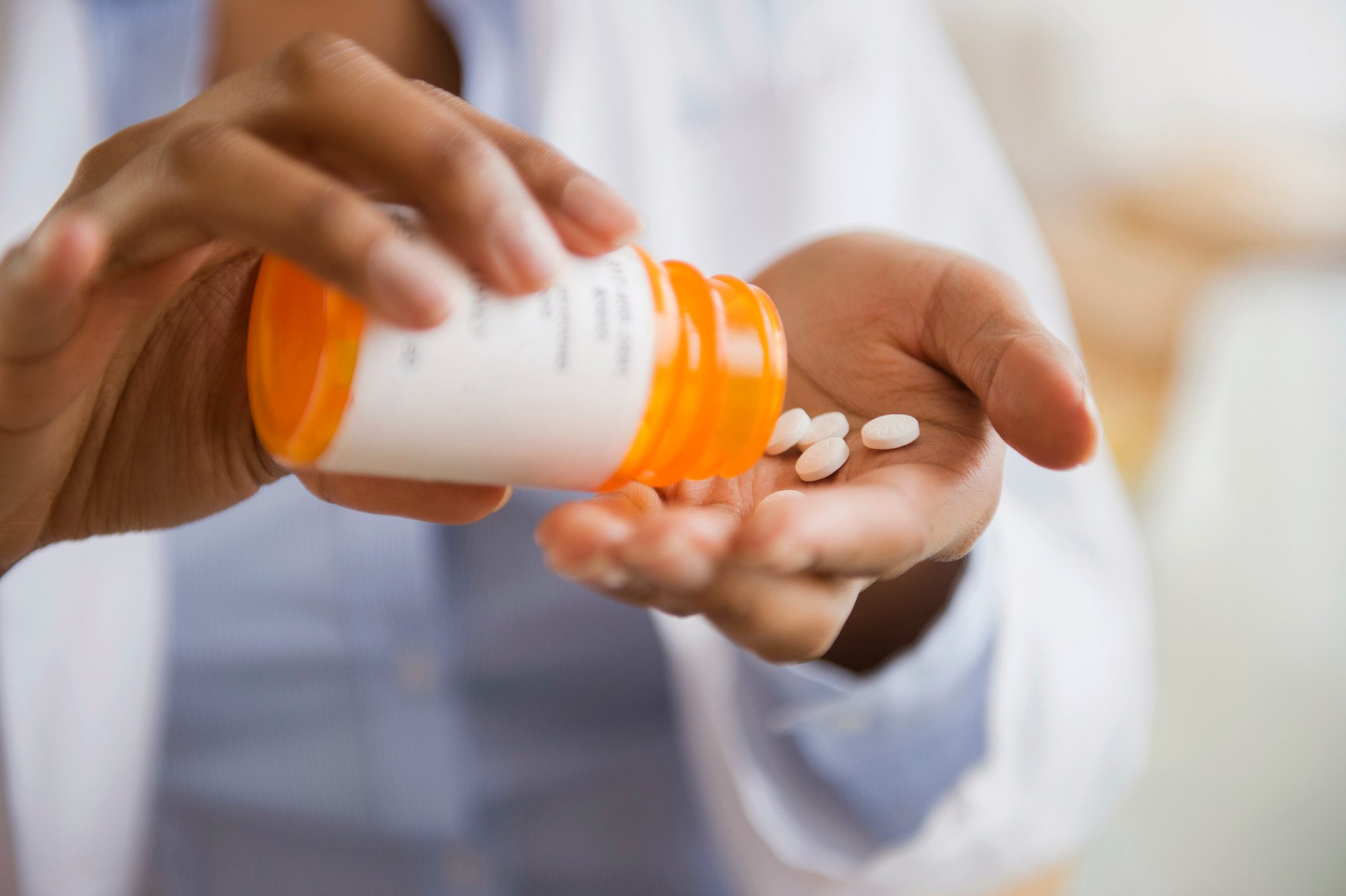 doctor pouring prescription pills into hand close up