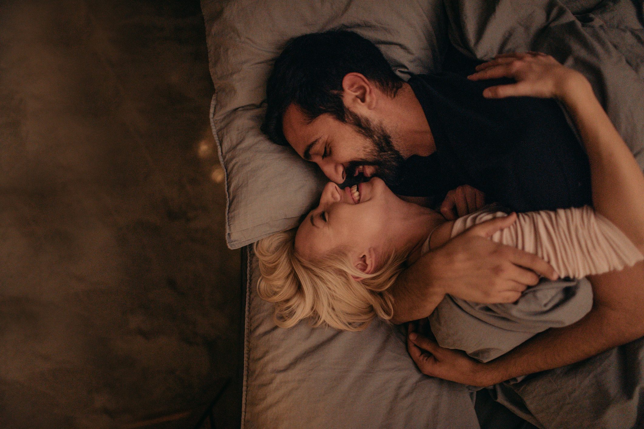 young man and woman cuddling and laughing in bed together
