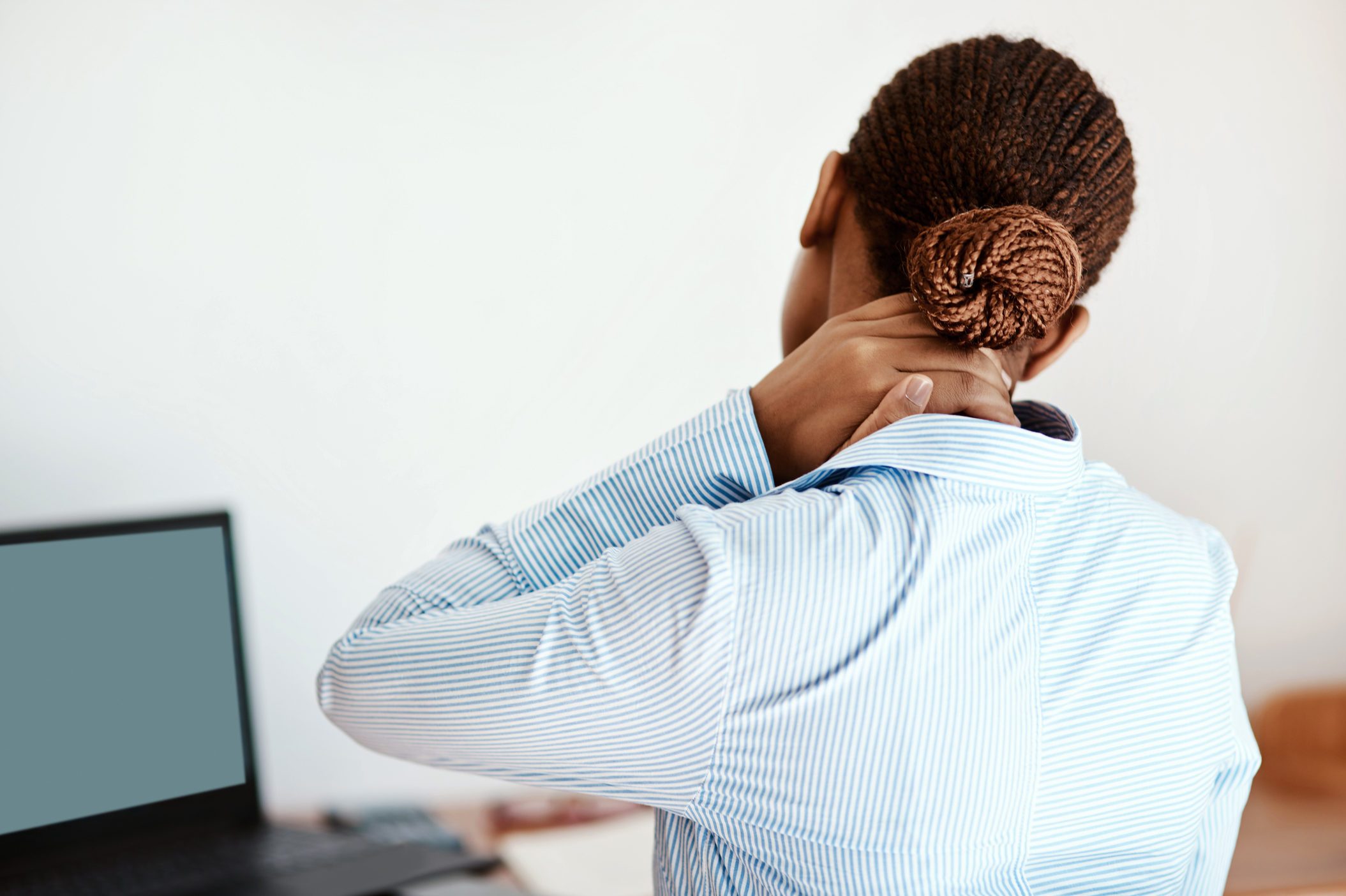 woman at computer with hand on her neck