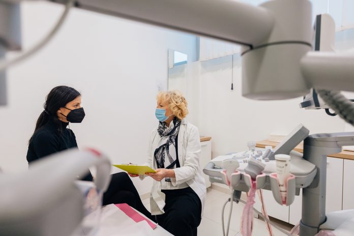 young woman talking to female doctor during breast examination appointment