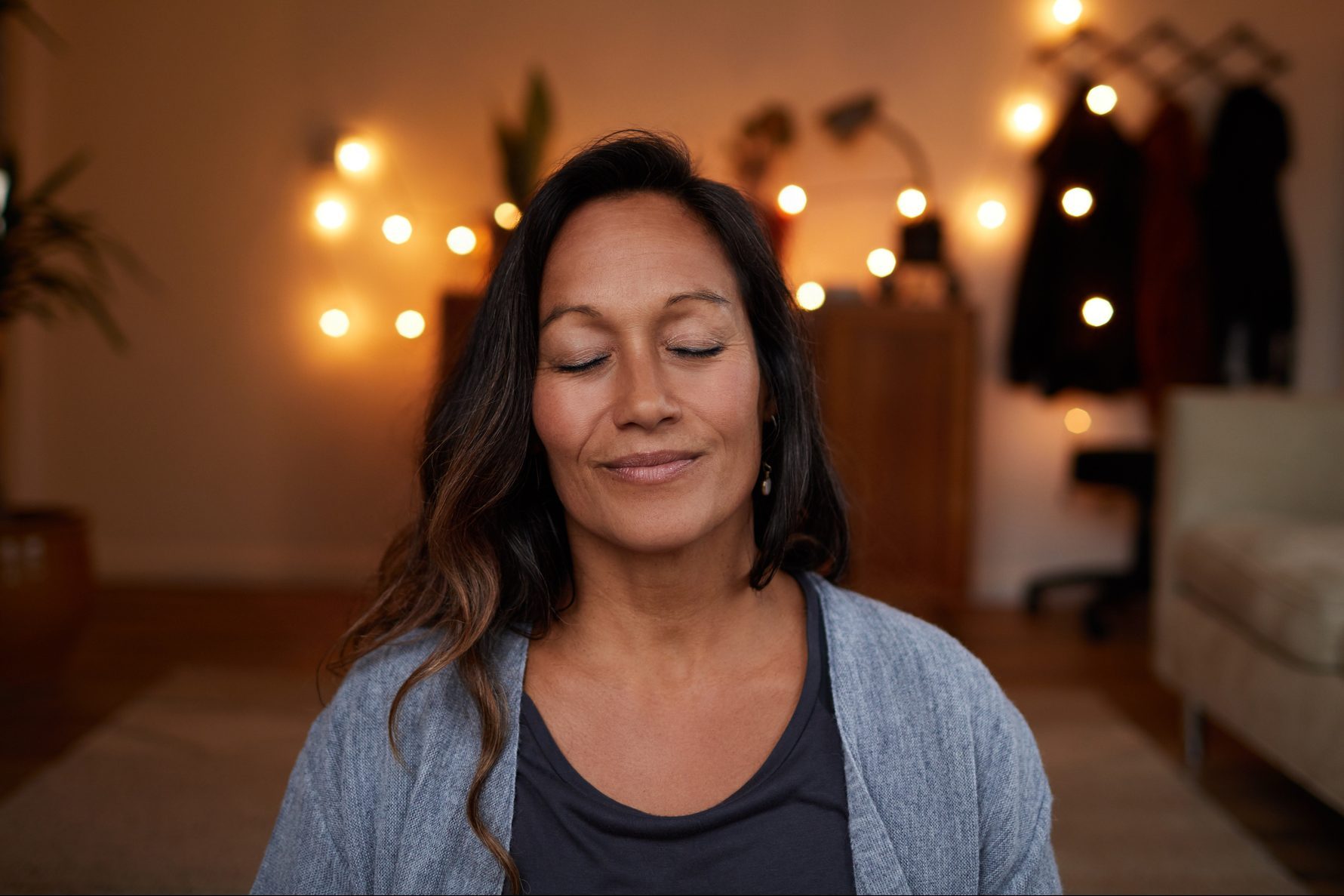 Serene mature woman smiling while meditating at home