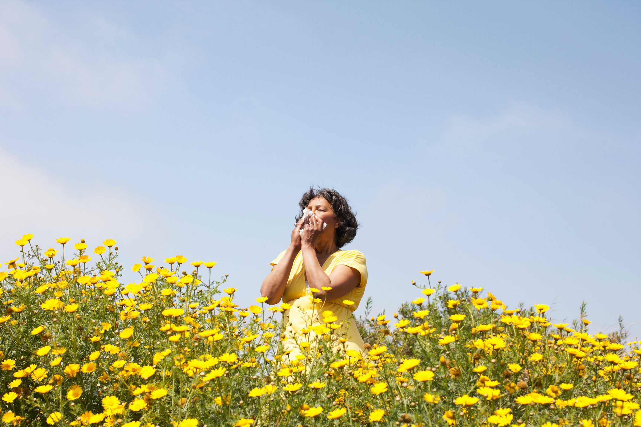 Mixed race woman in field of flowers enjoying scent