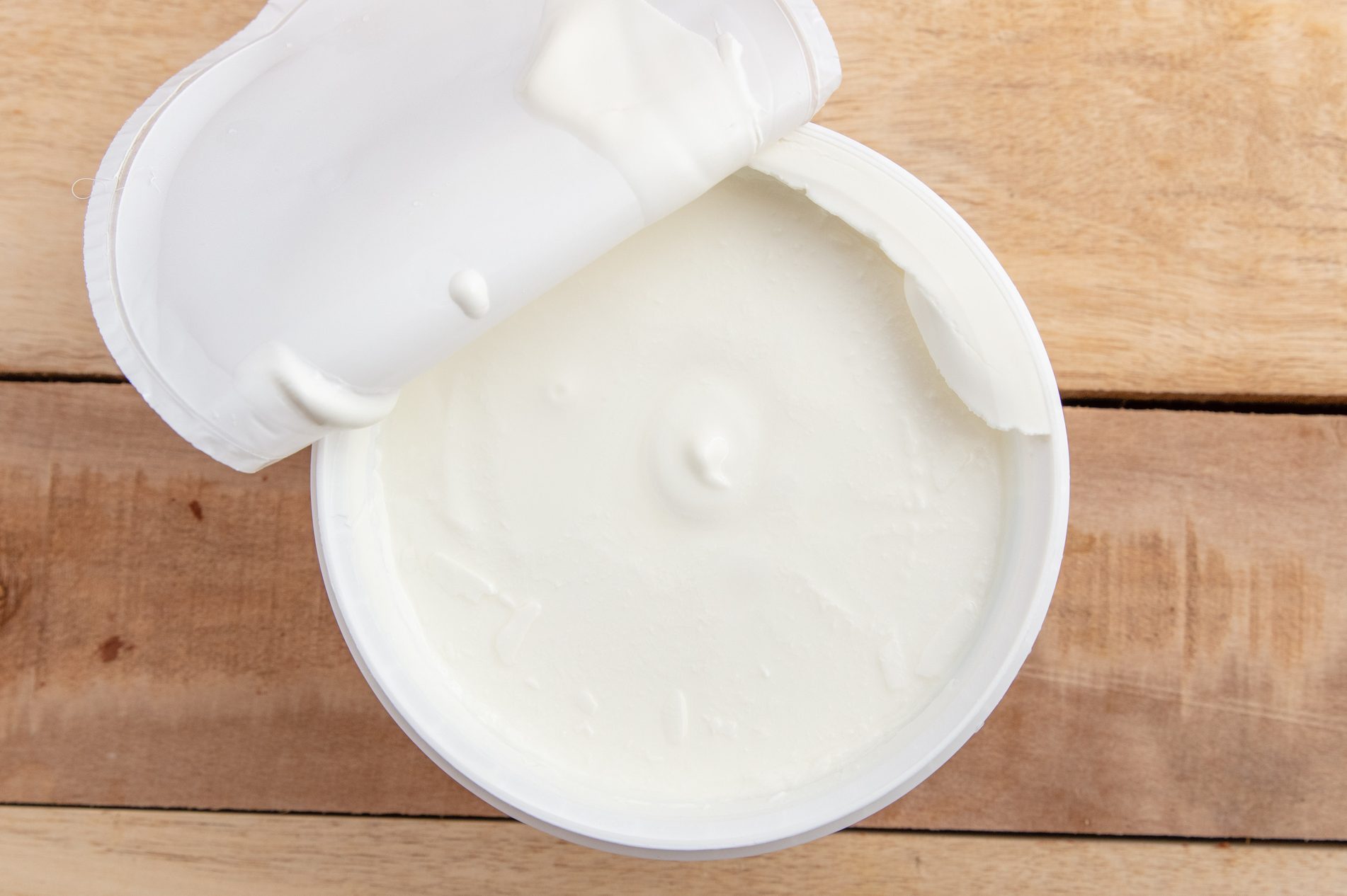open container of greek yogurt on wood table