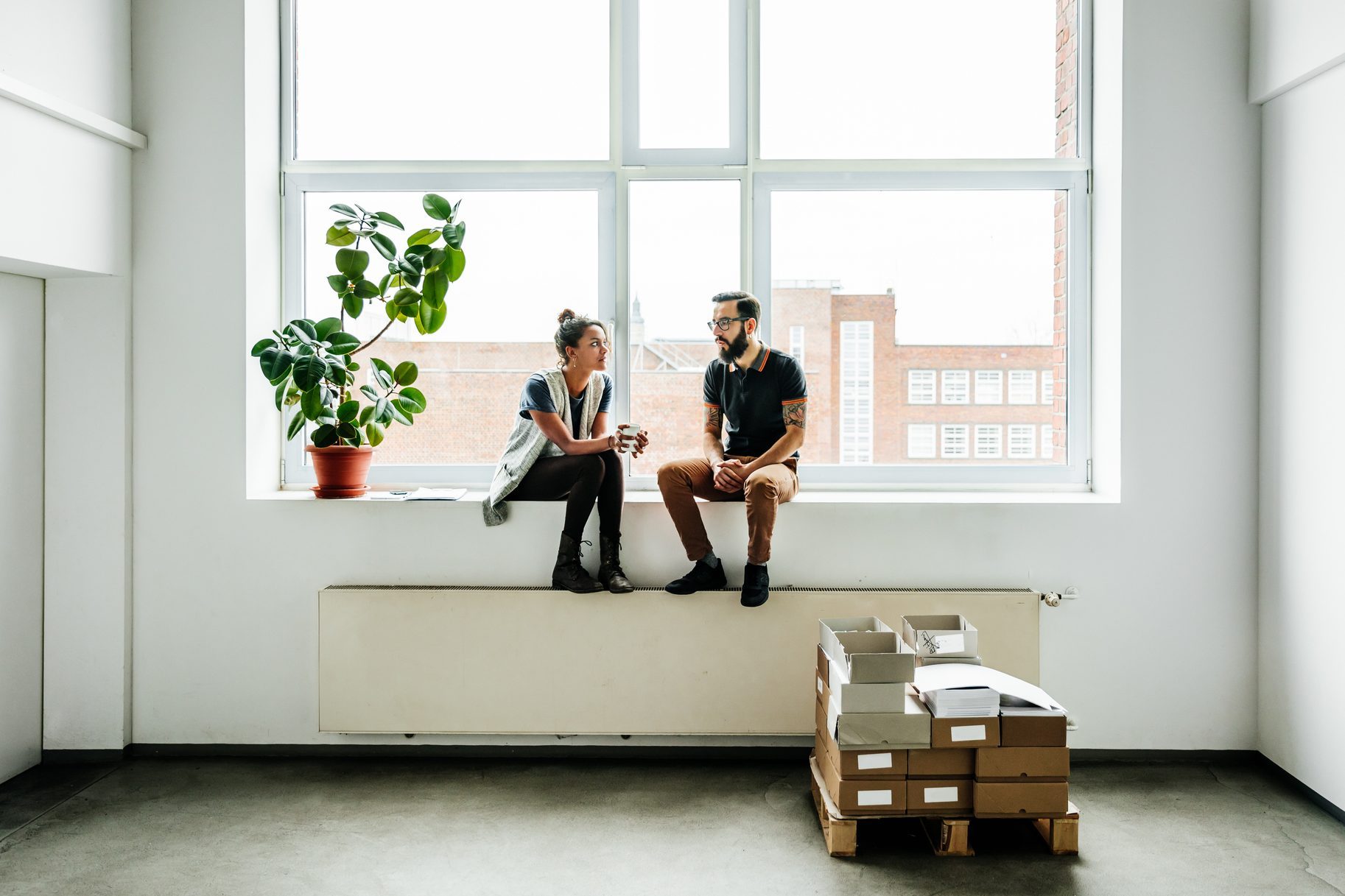 Young start up business people sitting in a window and talking