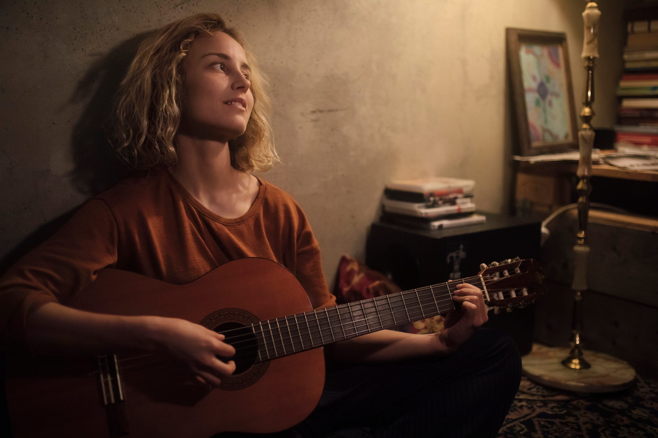 Young woman playing guitar at home at night