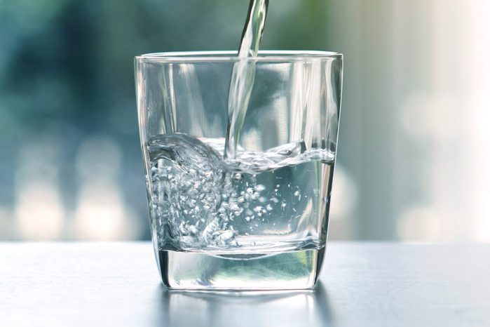 Close up the pouring purified fresh drink water from the bottle on table in living room