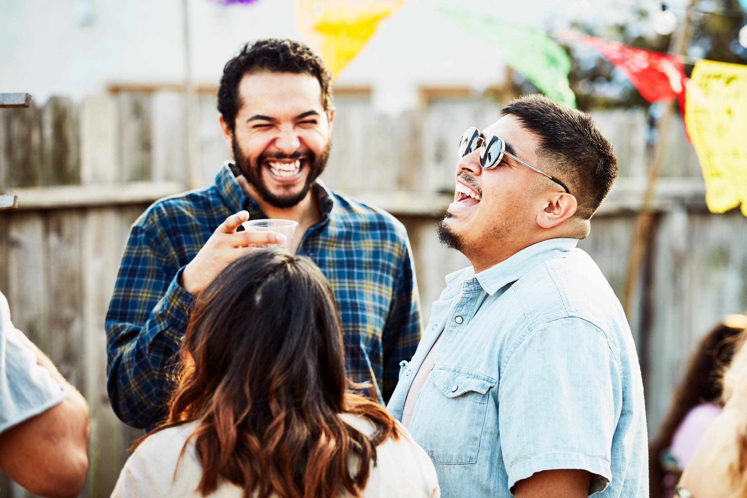 Laughing friends hanging out during backyard barbecue on summer evening