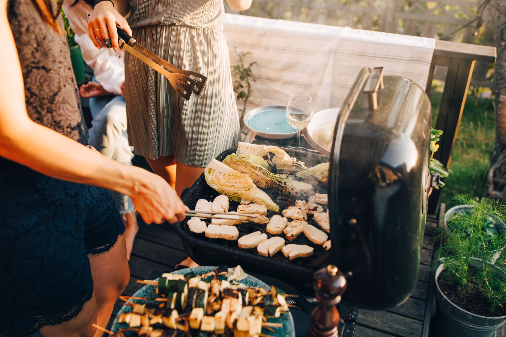 Midsection of female friends grilling food on barbecue grill at yard