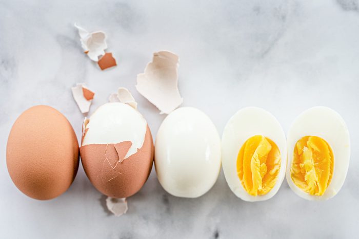 A row of hard boiled eggs showing the order of hard boiling an egg, peeling, and cutting.