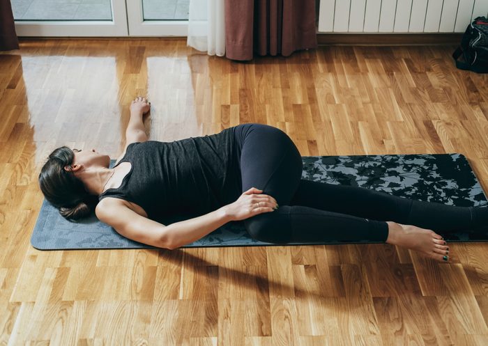 Woman Practicing Yoga in the Morning, Doing Jathara Parivartanasana Exercise