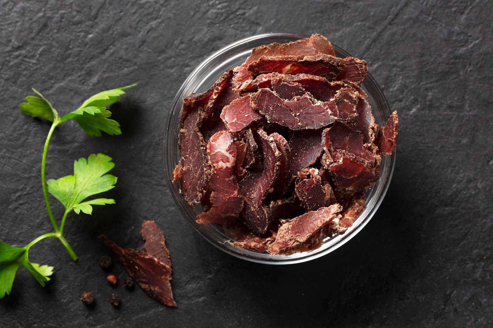 Bowl with jerky meat on a dark background