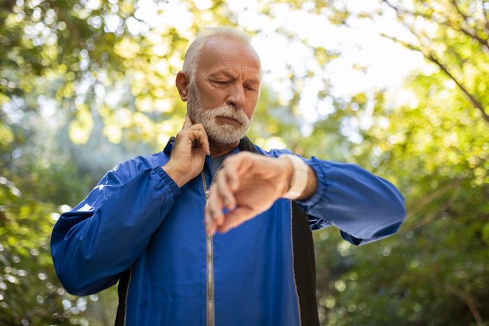 Senior Man Jogging taking a break measuring pulse