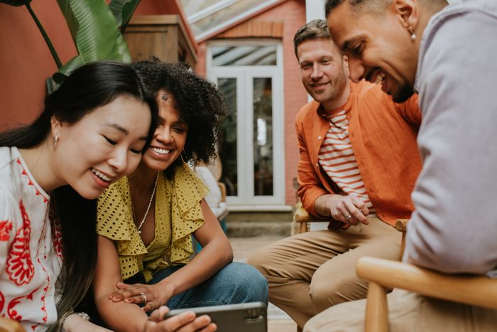 A group of 4 young people watch a video on a smart phone