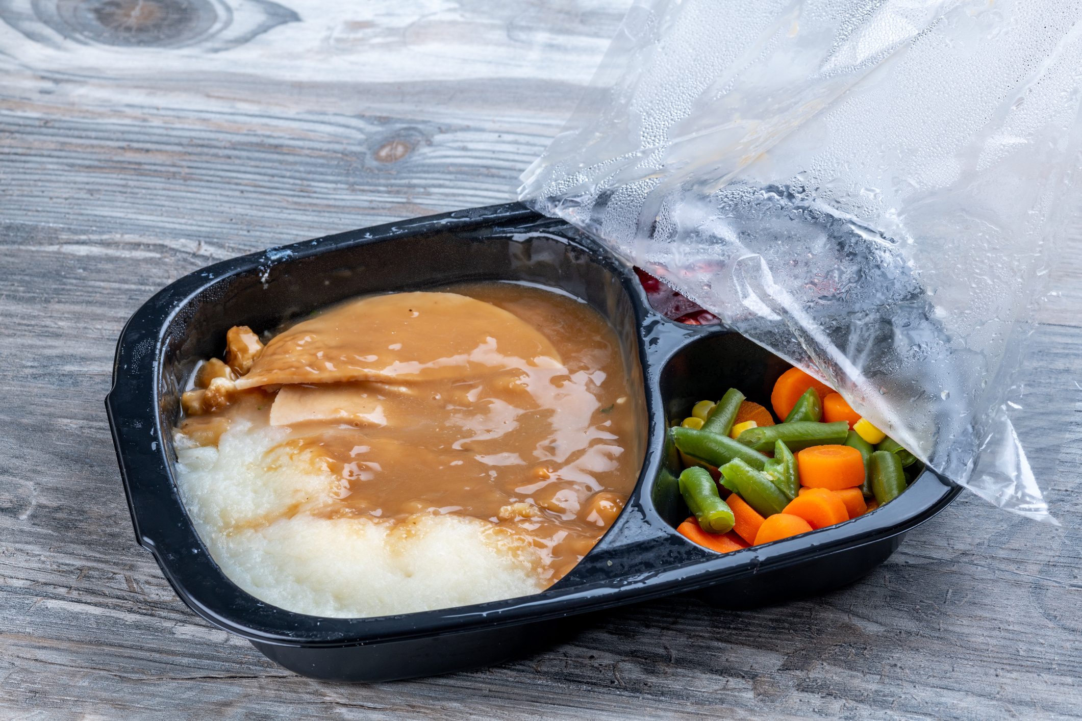 Pealing back the cellophane from a turkey TV dinner