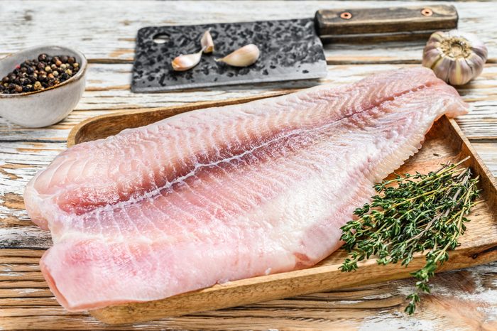 Fresh raw white fish fillet catfish with spices. White wooden background. Top view
