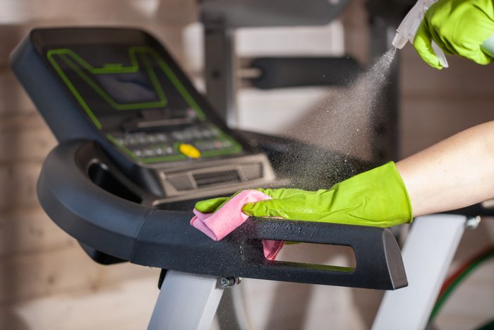 Spring cleaning in the home gym. Hand in a glove with a rag rubbing sports equipment.