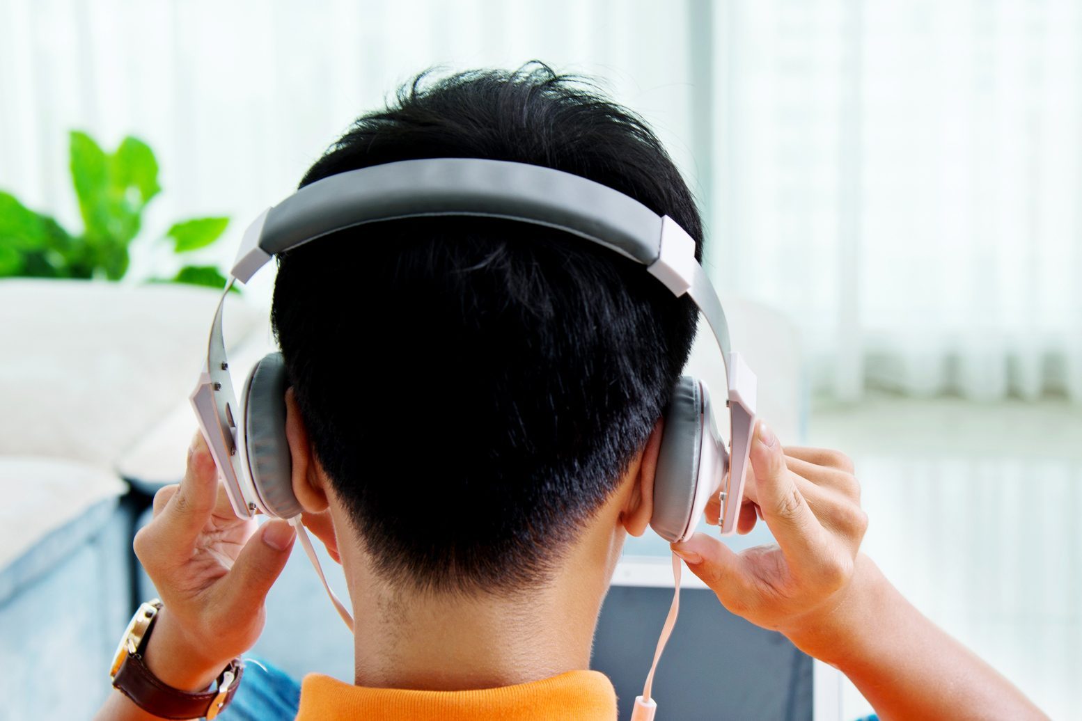 Rear view of asian man with laptop and headphone