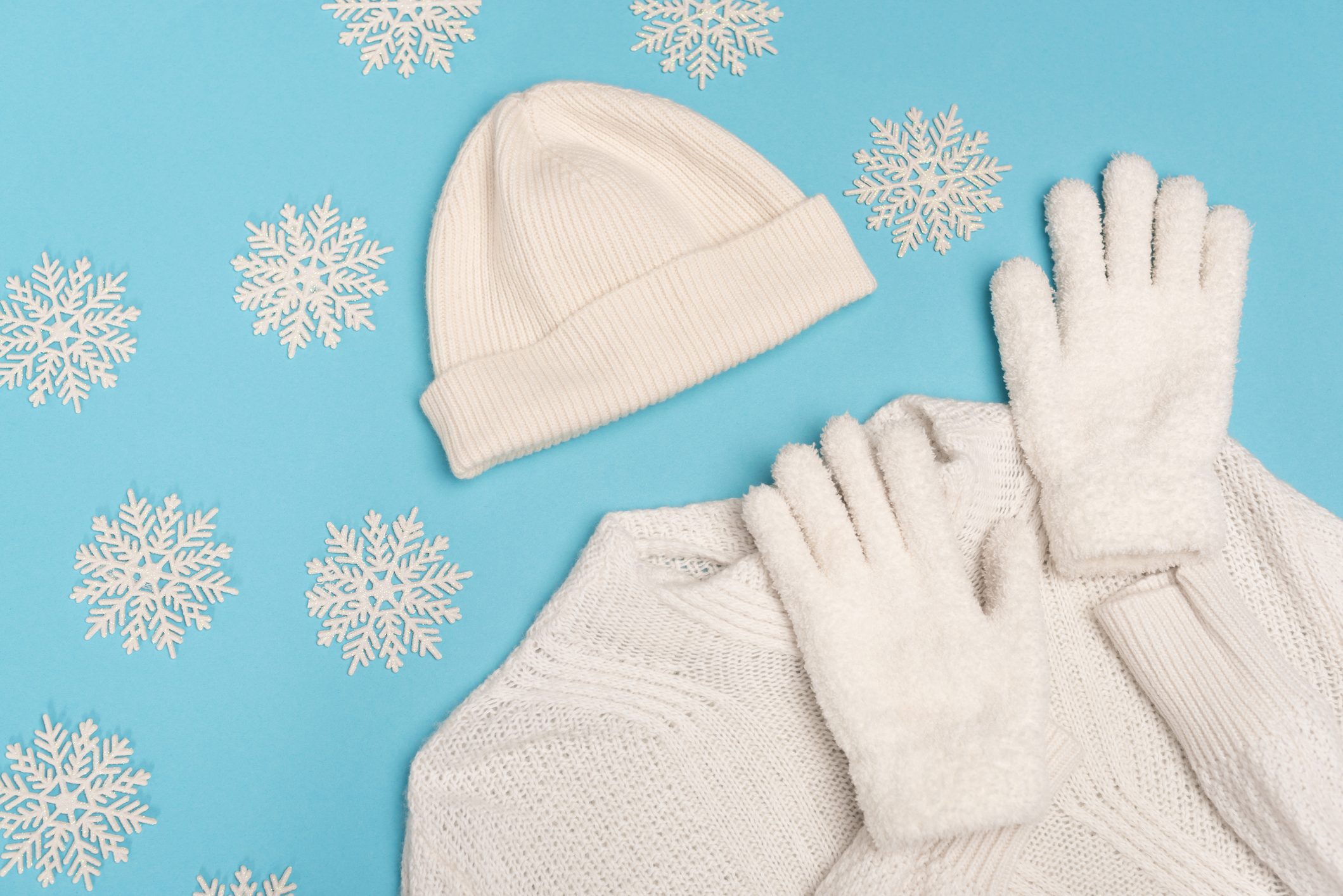 top view of winter white knitwear and snowflakes on blue background