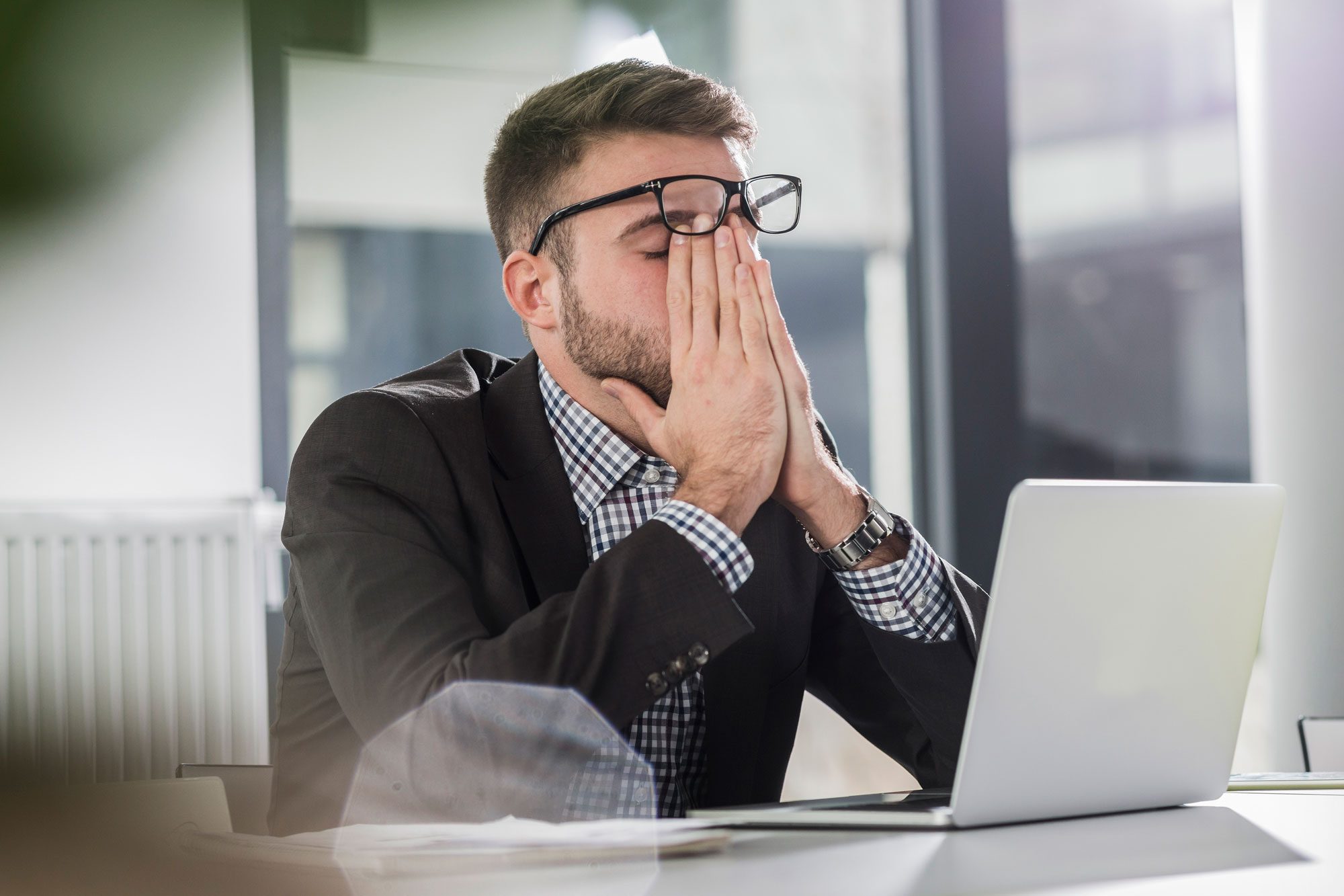 Exhausted Young Man With Laptop In Office