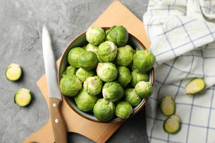 Composition with bowl of brussels sprout on grey background, top view