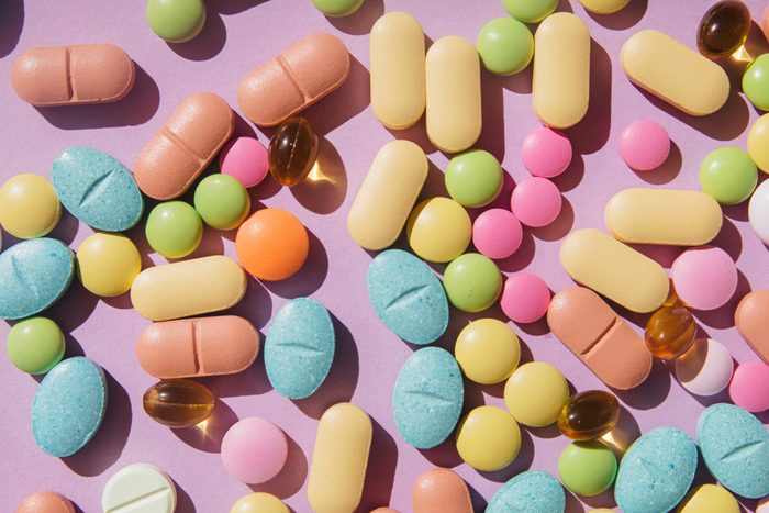 Colorful pills and capsules on purple background. Minimal medical concept. Flat lay, top view