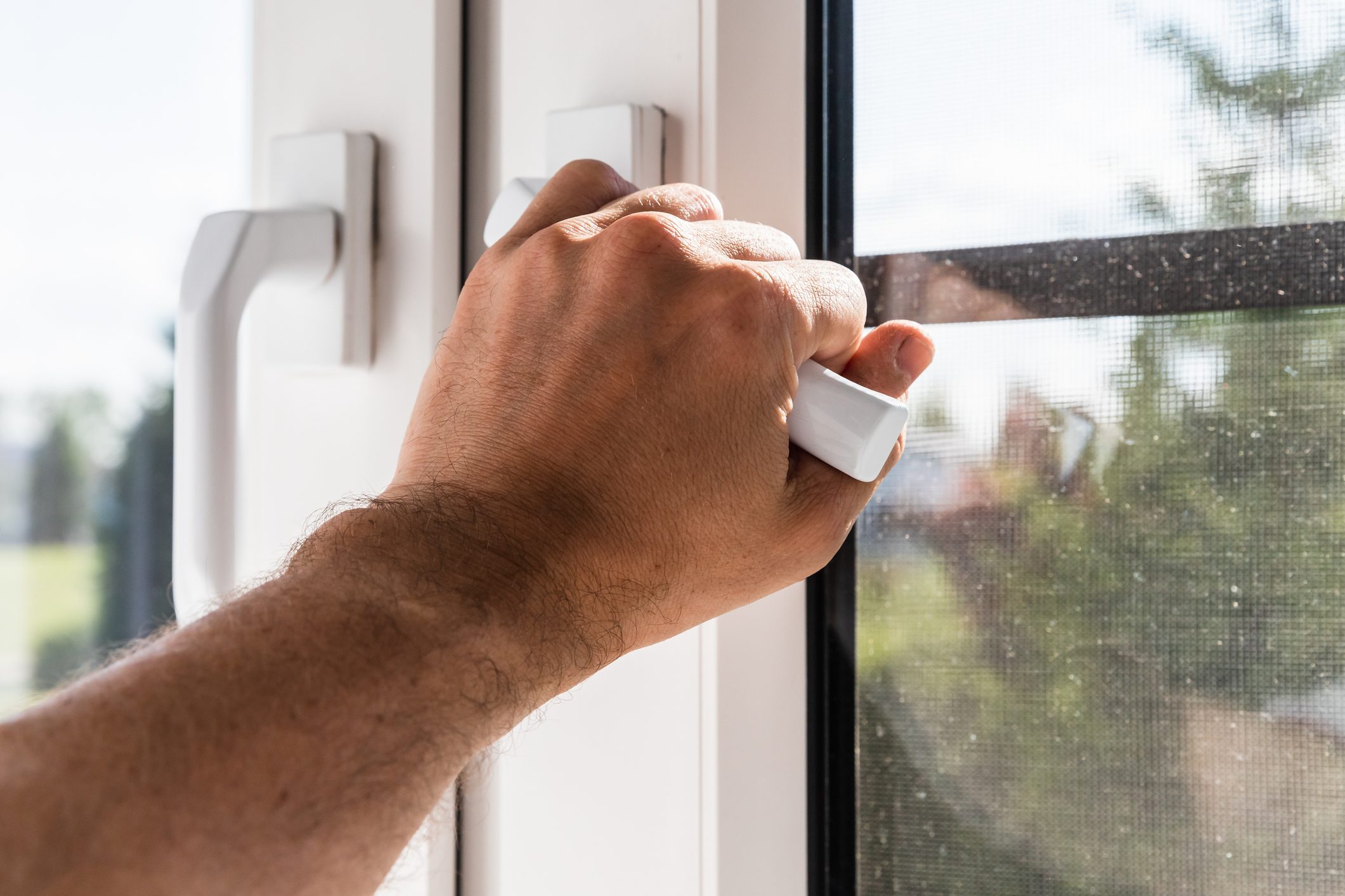 Male hand opening modern plastic window on a sunny day