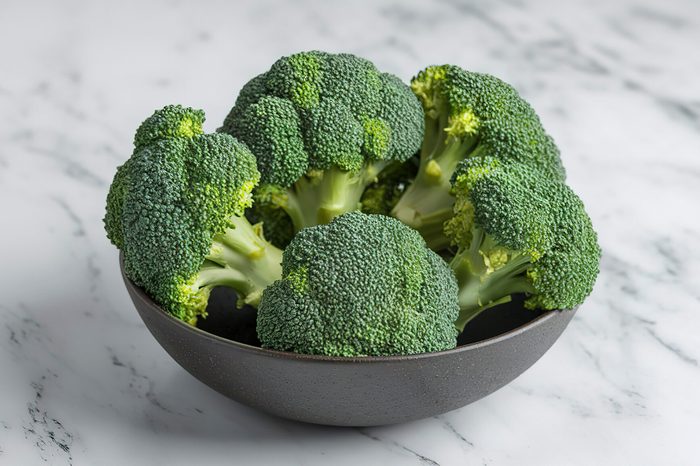 A photo of a bowl of broccoli on a marble surface